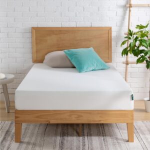 Hochwertige Matratze auf einem Holzbettrahmen, modernes Schlafzimmer mit weißer Wand und grüner Pflanze, ideal für gesunden Schlaf und Komfort.