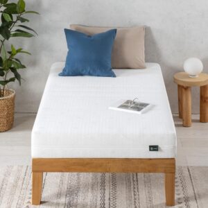 Weiches Matratzenbild mit einem weißen Bezug, zwei Kissen in Blau- und Beigeton, ein Nachttisch mit Lampe, ein Pflanzenkübel und ein aufgeschlagenes Buch auf dem Bett. Perfekt für erholsamen Schlaf.